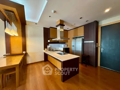 Modern kitchen with island, wooden flooring, and sleek appliances in a stylish apartment.