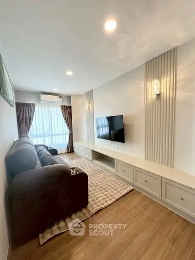 Modern living room with cozy sofa and wall-mounted TV, featuring elegant lighting and wooden flooring.