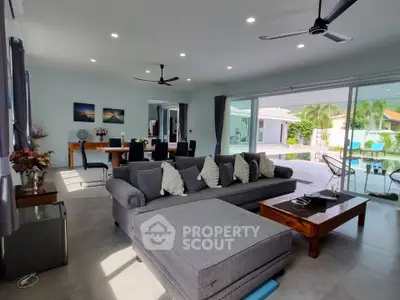 Spacious modern living room with large windows and pool view, perfect for relaxation and entertaining.