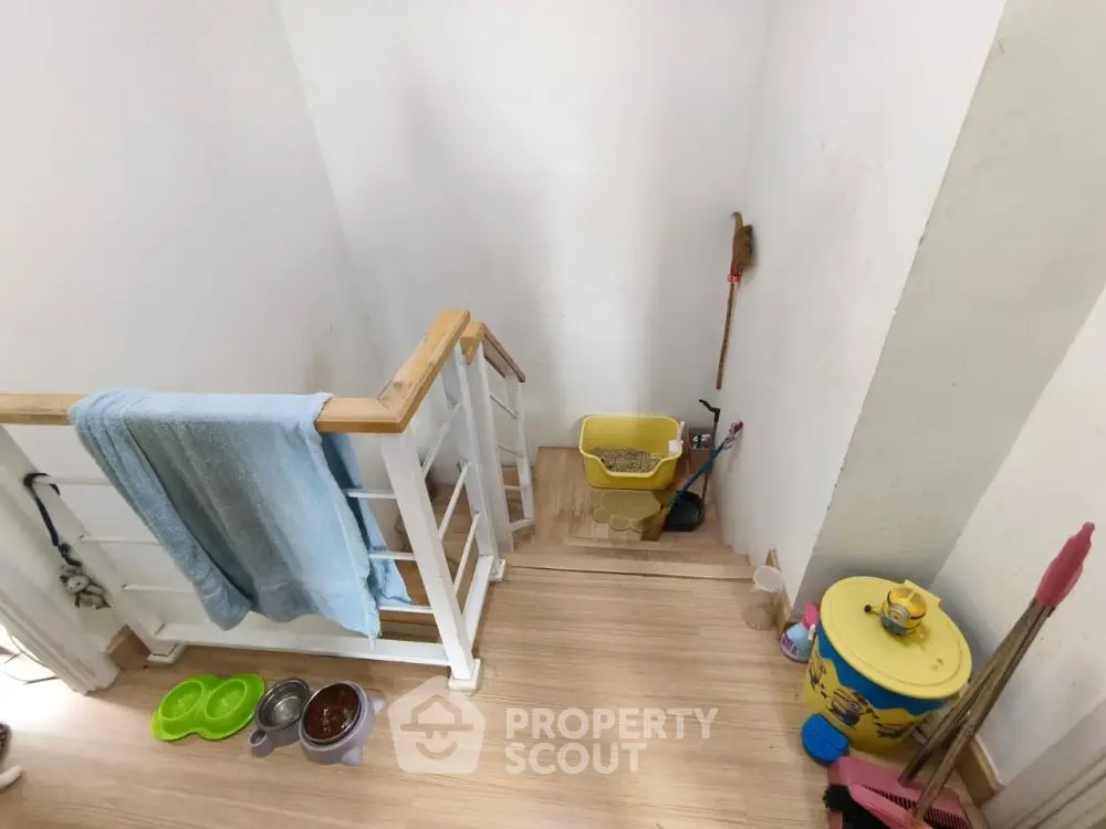 Cozy staircase with wooden railing and cleaning supplies, perfect for a tidy home.