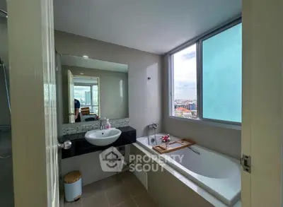 Modern bathroom with large window and bathtub offering city views.