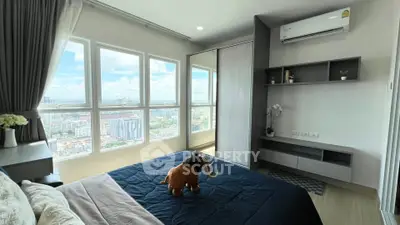 Modern bedroom with large windows offering stunning city views, featuring sleek furniture and air conditioning.