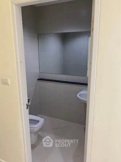 Compact bathroom with modern tiles and sleek fixtures, perfect for efficient space utilization.