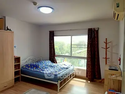 Bright bedroom with large window and wooden flooring, featuring a cozy bed and air conditioning.