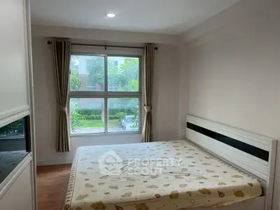 Cozy bedroom with large window and garden view, featuring a comfortable bed and elegant curtains.