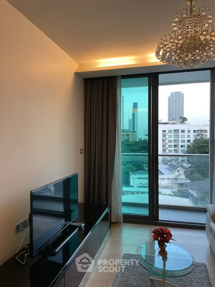 Modern living room with city view, elegant chandelier, and sleek furniture in a high-rise apartment.