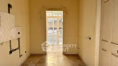 Spacious interior hallway with tiled floor and large window, perfect for renovation.