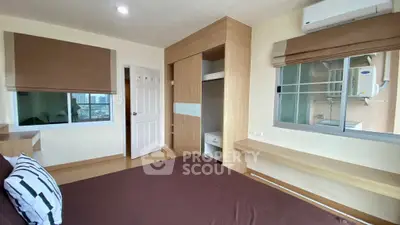 Modern bedroom with built-in wardrobe and city view window, featuring air conditioning.