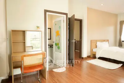 Bright bedroom with wooden flooring, cozy bed, and study desk, perfect for relaxation and productivity.