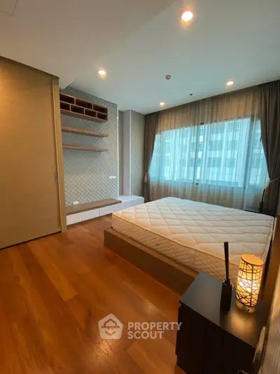 Spacious bedroom with wooden flooring and large window in modern apartment