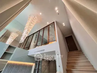 Luxurious modern interior with elegant chandeliers and staircase in a spacious living area.