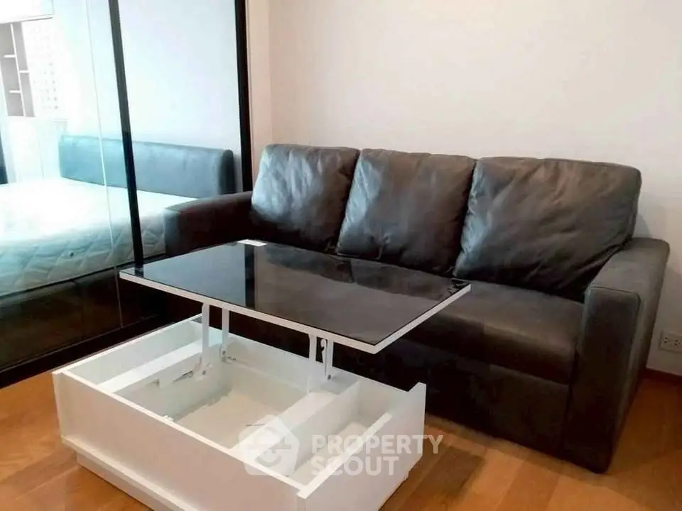 Modern living room with sleek black leather sofa and innovative lift-top coffee table.