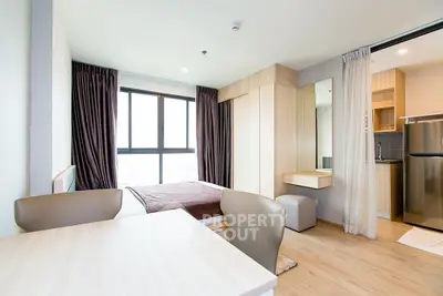 Modern studio apartment with cozy bedroom and kitchenette, featuring sleek furniture and natural light.