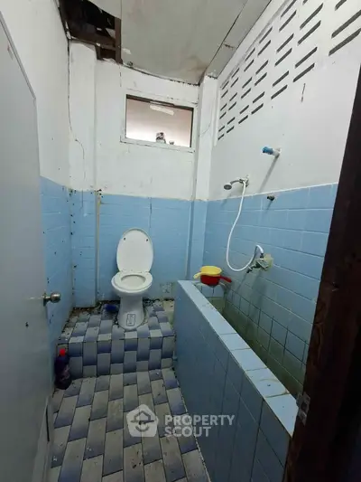 Compact bathroom with blue tiles and basic fixtures, featuring a shower and toilet.