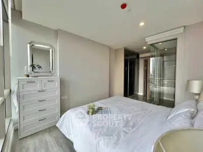 Modern bedroom with elegant decor and city view, featuring a cozy bed and stylish dresser.