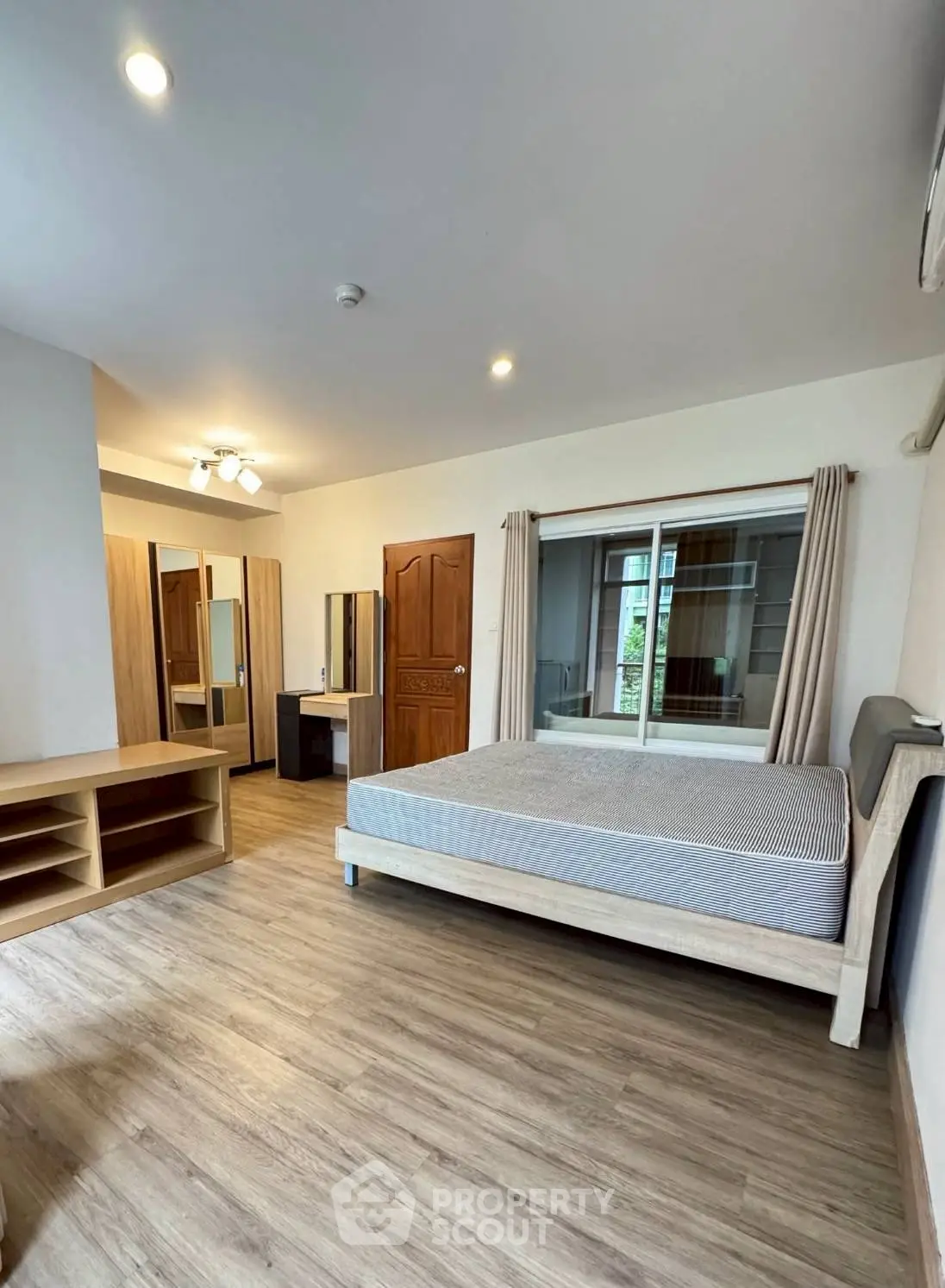 Spacious bedroom with modern furnishings and large window in a stylish apartment.