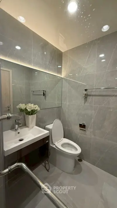 Modern bathroom with sleek gray tiles and elegant fixtures, featuring a stylish vanity and contemporary lighting.