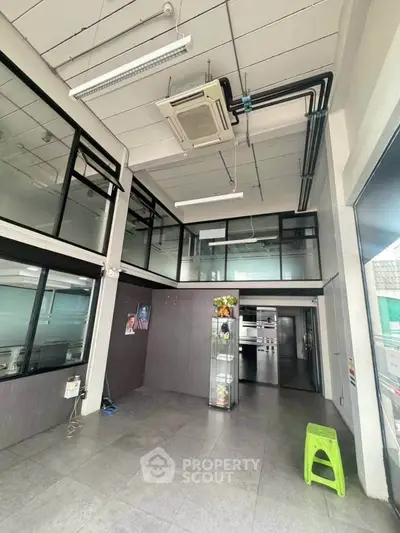 Spacious modern interior with high ceilings and glass partitions, ideal for commercial use.