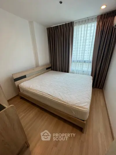 Cozy bedroom with wooden flooring and large window for natural light