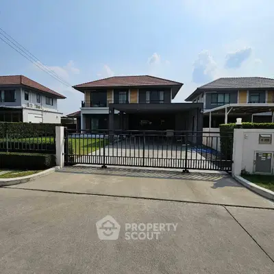 Modern two-story house with gated driveway and manicured lawn in a suburban neighborhood.