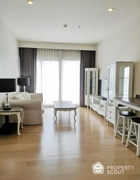 Elegant living room with polished wooden floors, ample natural light, and tasteful neutral-toned furniture, perfect for a modern lifestyle.