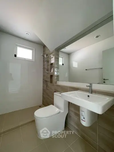 Modern bathroom with sleek fixtures and neutral tiles, featuring a spacious shower area.