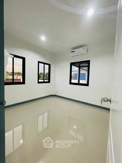 Spacious unfurnished room with large windows and air conditioning, perfect for customization.