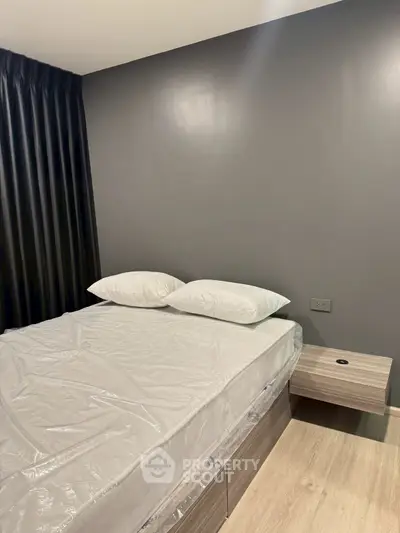 Modern bedroom with sleek design and neutral tones, featuring a comfortable bed and stylish side table.