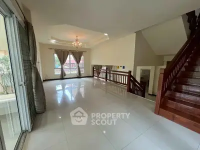 Spacious living room with elegant chandelier and wooden staircase in modern home.