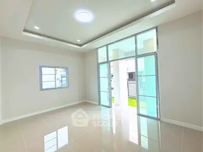 Spacious modern living room with large windows and glossy tiled floor, perfect for natural light lovers.