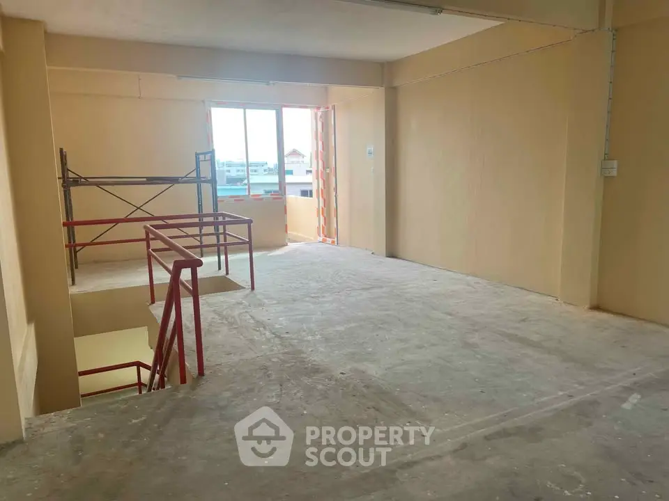 Spacious unfinished interior with large window and staircase, ideal for customization.