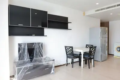 Modern apartment interior with sleek black furniture and appliances, featuring a dining area and spacious layout.