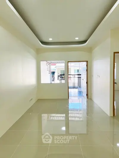 Spacious and bright living room with glossy tiled floors and modern ceiling design.