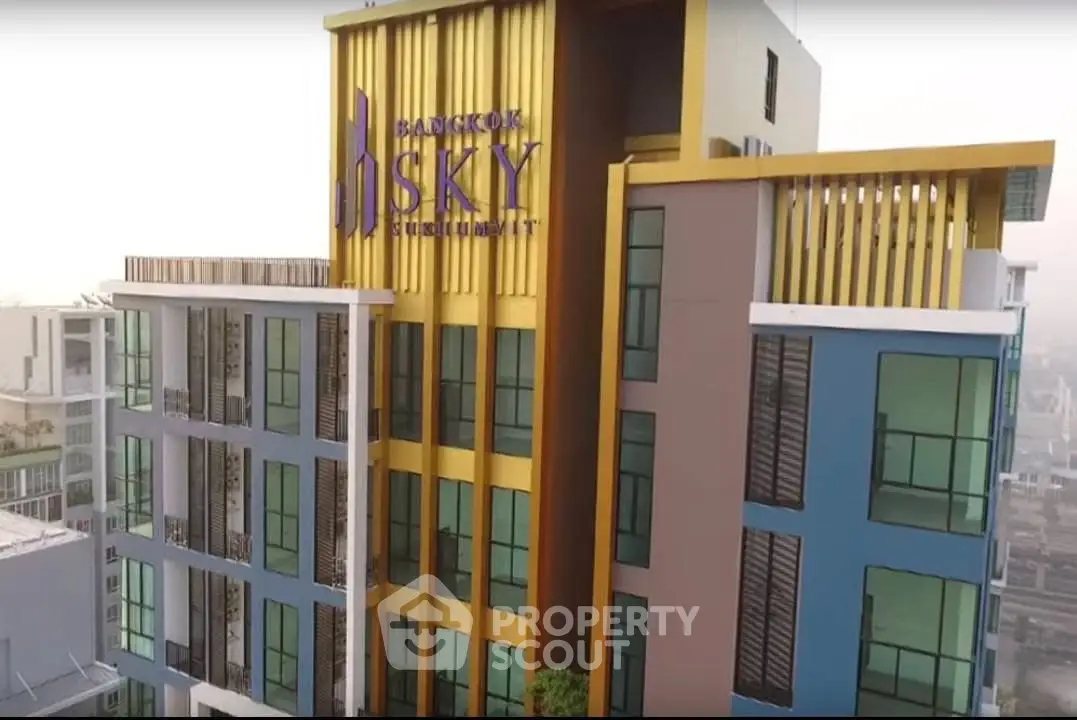 Modern high-rise building with colorful facade and large windows in urban setting.