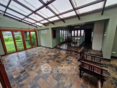 Spacious open-plan living area with rustic tile flooring and garden view, perfect for entertaining.