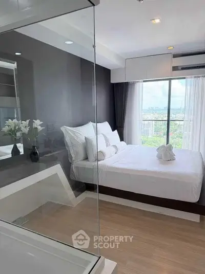 Modern bedroom with glass wall and city view, featuring elegant decor and natural light.