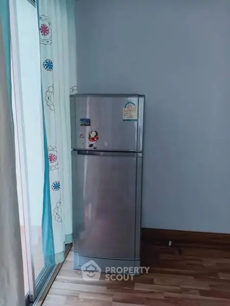 Modern kitchen corner with sleek stainless steel fridge and stylish curtains