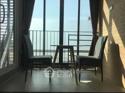 Charming balcony with elegant seating and expansive glass doors, perfect for relaxation and enjoying the view.