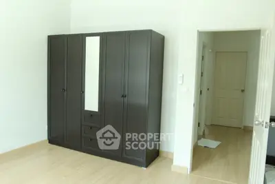 Spacious bedroom with elegant dark wardrobe and light wooden flooring