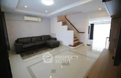 Spacious modern living room with elegant staircase and sleek leather sofa