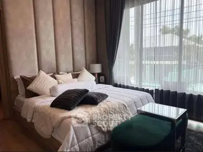 Luxurious bedroom with elegant decor and large window offering natural light.