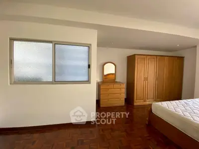 Spacious bedroom with wooden furniture and parquet flooring