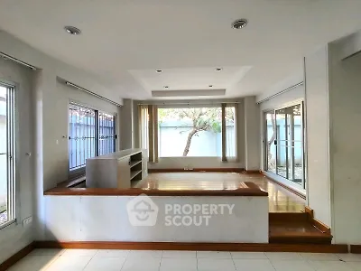 Spacious living room with large windows and elevated wooden flooring, perfect for natural light lovers.