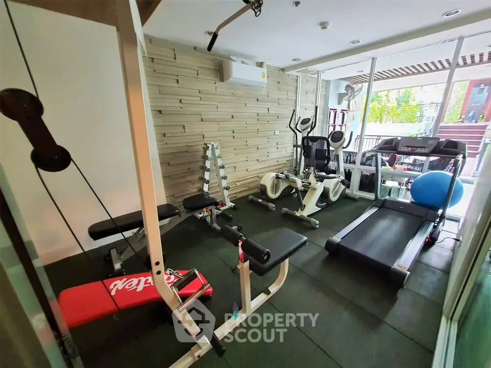 Modern gym with exercise equipment and natural light in a residential building.