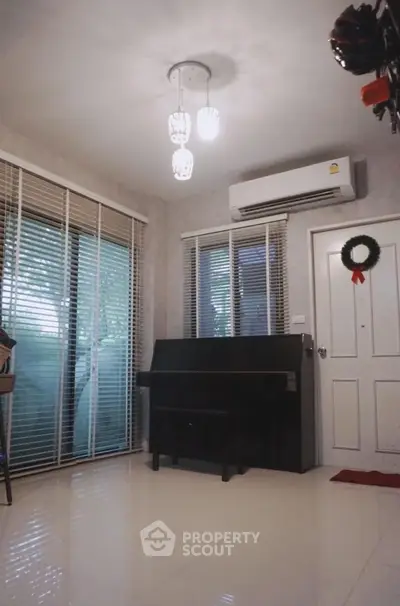 Charming living room with piano and modern lighting, featuring large windows and air conditioning.