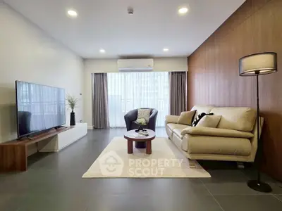 Spacious modern living room with elegant decor and large TV, perfect for relaxation.