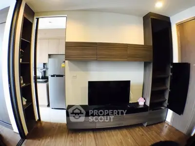 Modern living room with sleek wooden entertainment center and open kitchen view.