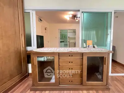 Spacious living room with elegant wooden furniture and sliding glass doors in modern apartment.