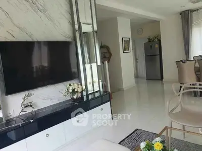 Elegant living room with modern decor and large TV, featuring marble accents and stylish furniture.