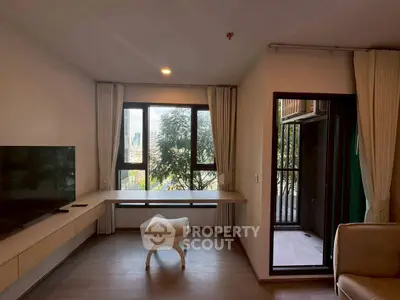 Modern living room with large windows and balcony access, featuring a sleek TV setup.